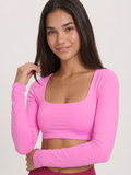 A woman wearing a bright pink long-sleeve crop top with a square neckline, shown against a plain light background.