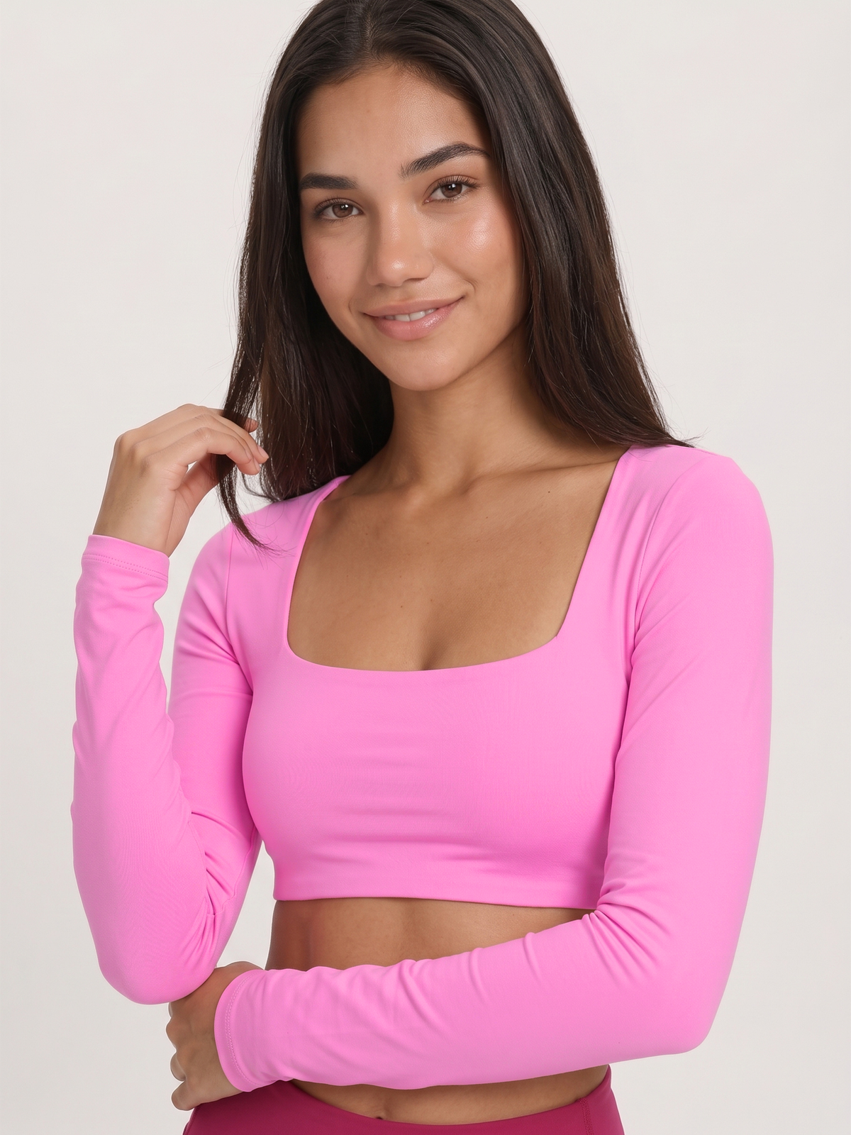 A woman wearing a bright pink long-sleeve crop top with a square neckline, shown against a plain light background.